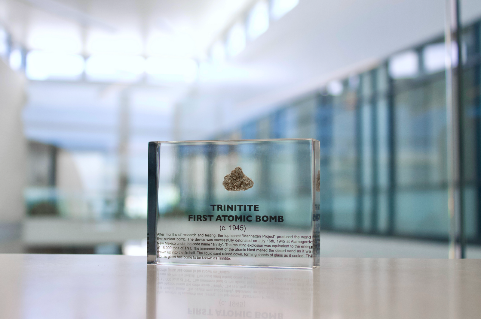 Trinitite specimen from the first atomic bomb test facing up on a textured background, collector gift