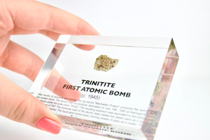 Trinitite specimen held in hand above display case on white background, rare collector gift