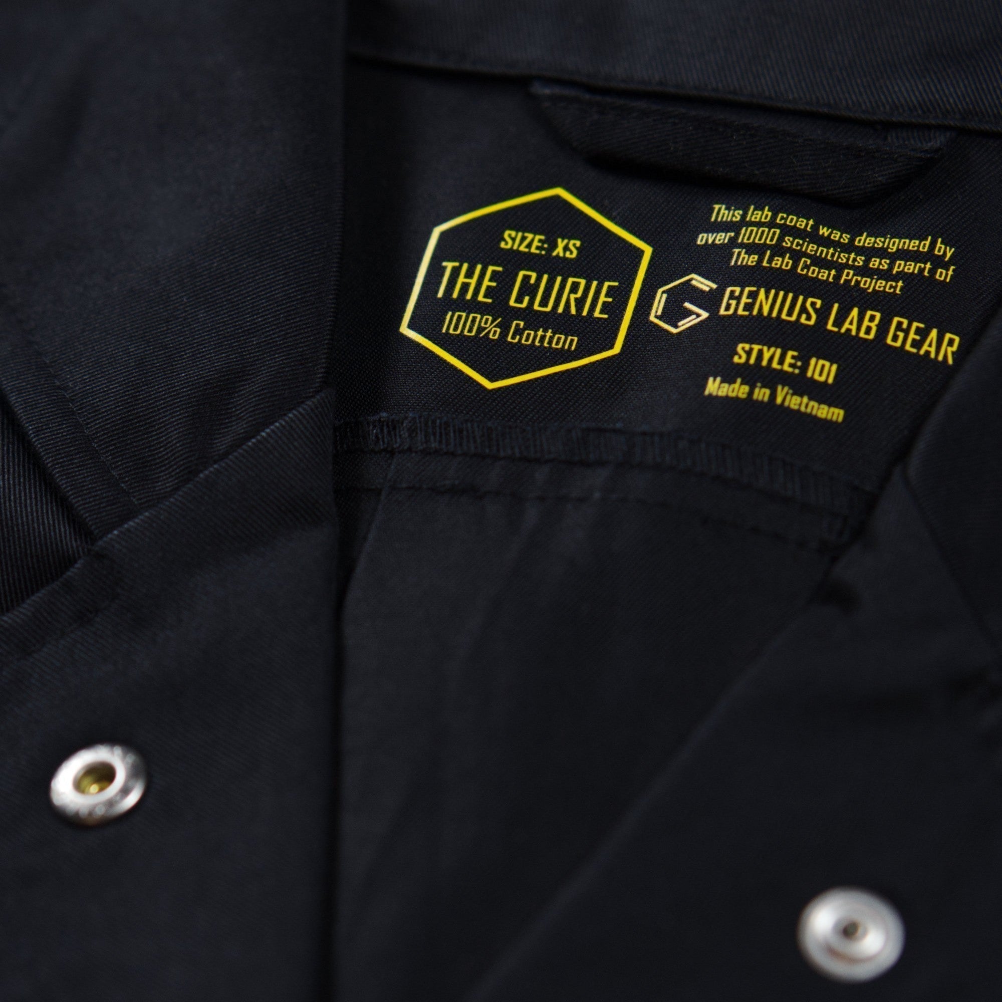 the marie curie black cotton lab coat collar and metal snaps close up
