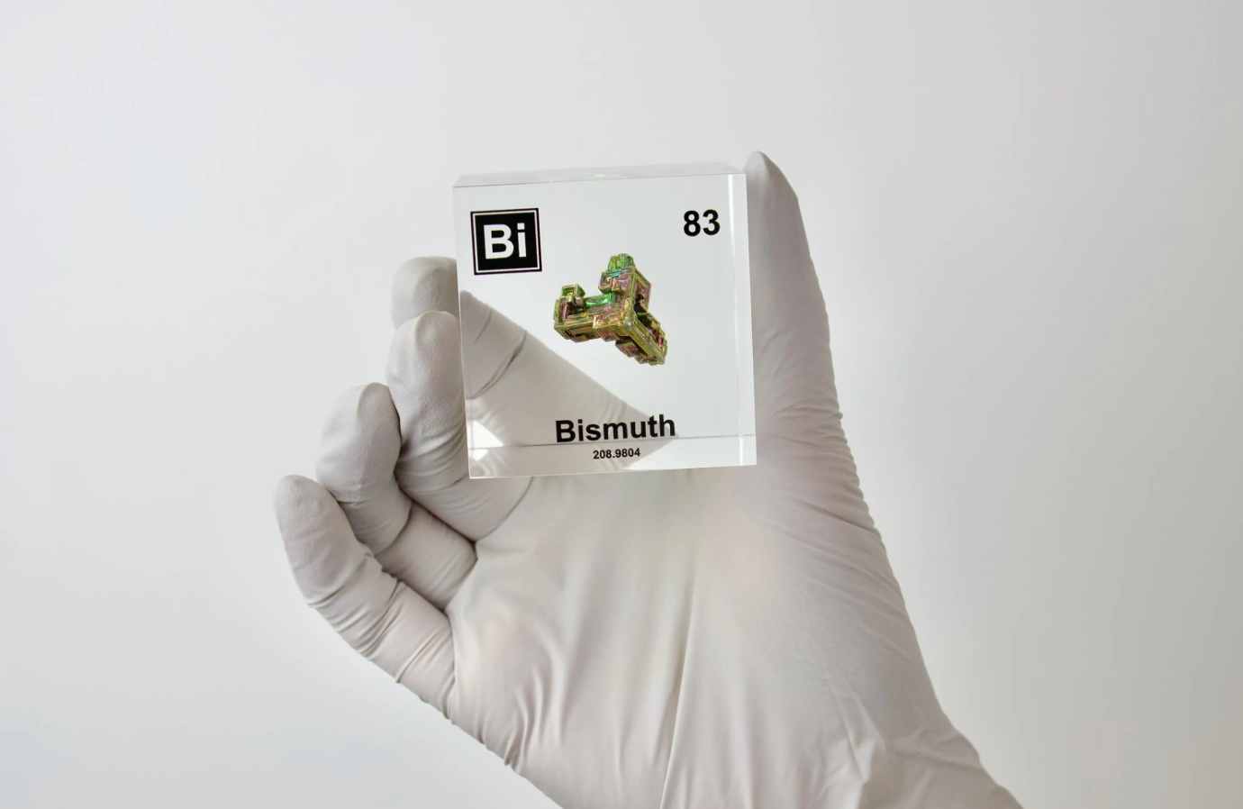 Bismuth element cube held in hand to show scale on white background, collector gift