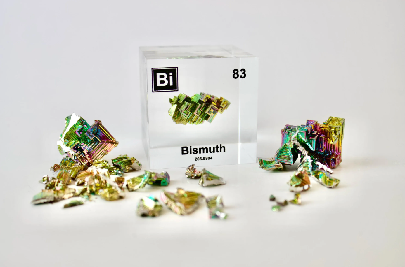 Bismuth element cube beside a raw bismuth crystal sample on white background, collector gift