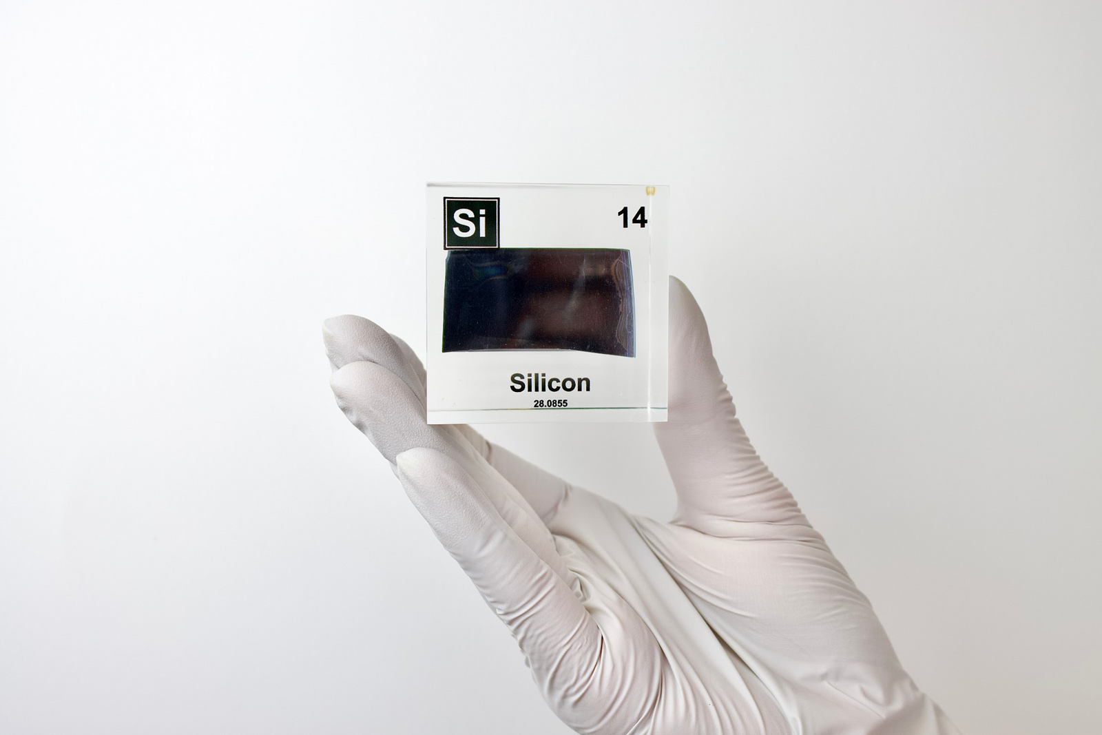 Silicon element cube held in hand to show scale on white background, collector gift