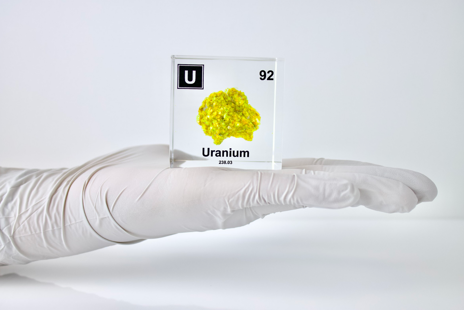 Uranium element cube held in hand front view on white background, collector gift