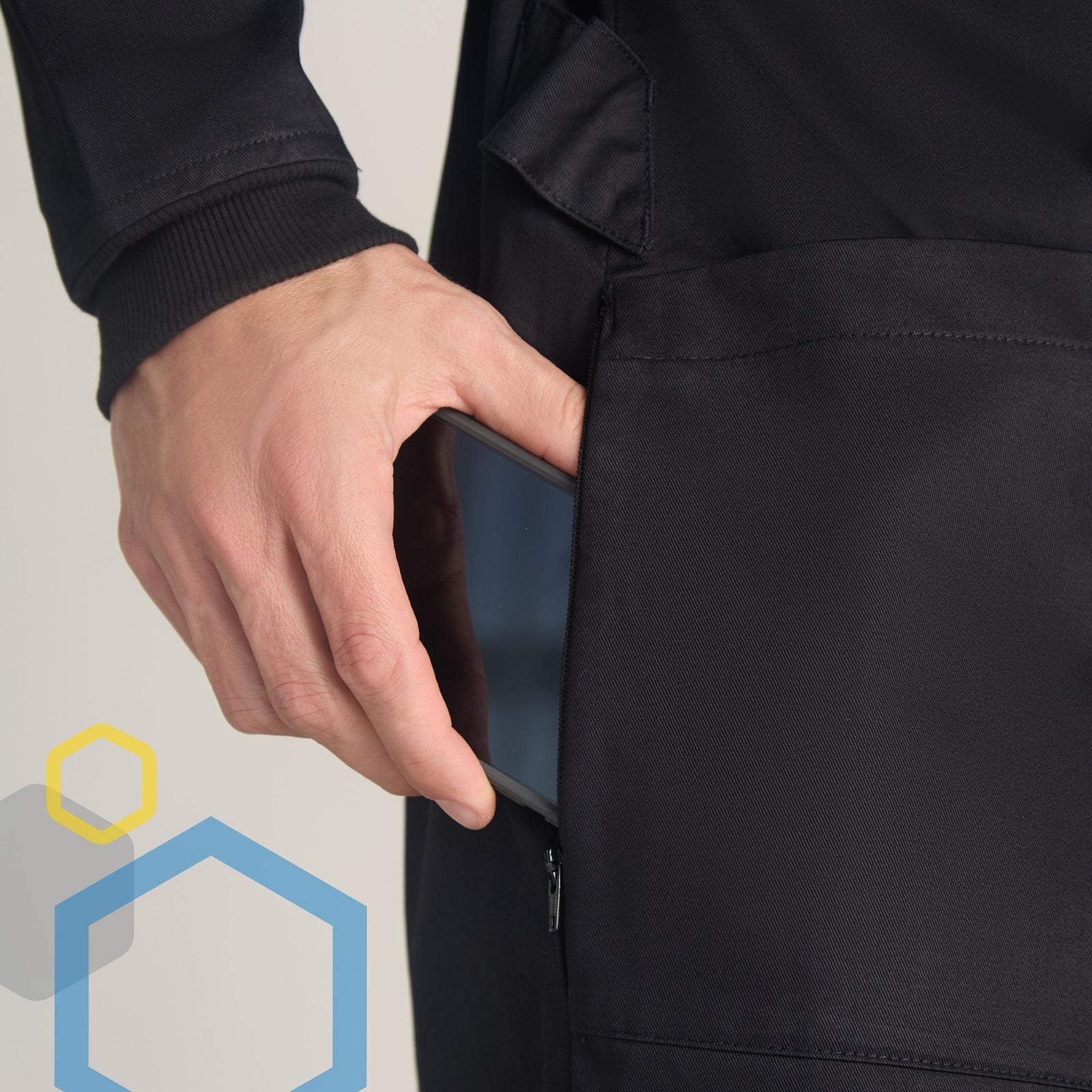 Hand inserting cell phone into zipper side access pants pockets in black lab coat