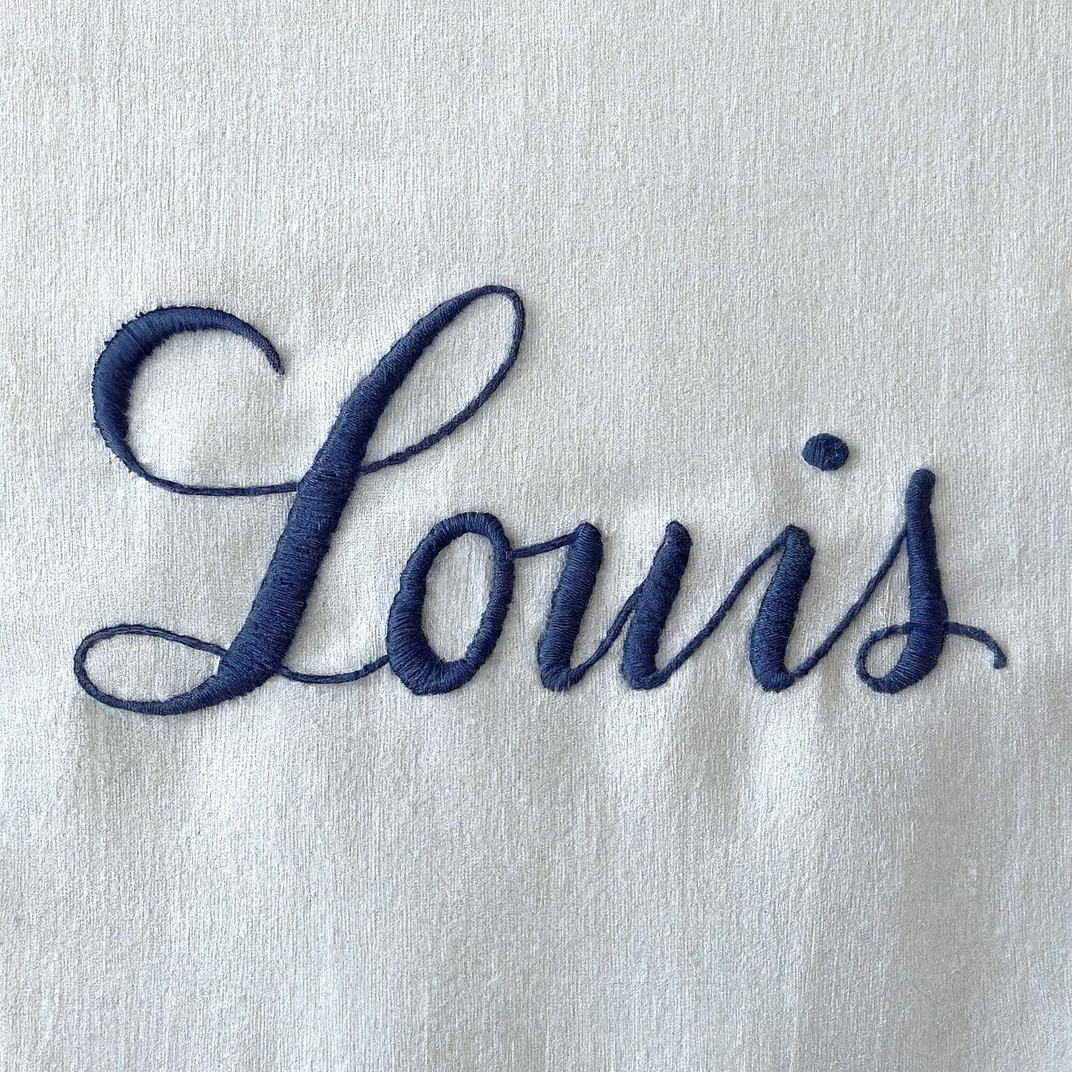 Louis lab coat chest pocket close-up with brand name and custom text embroidered in navy thread