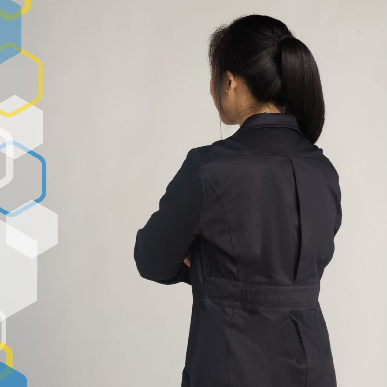 petite female scientist wearing womens extra small black lab coat with arms crossed showing back pleats that expand when reaching forward over a chemistry bench
