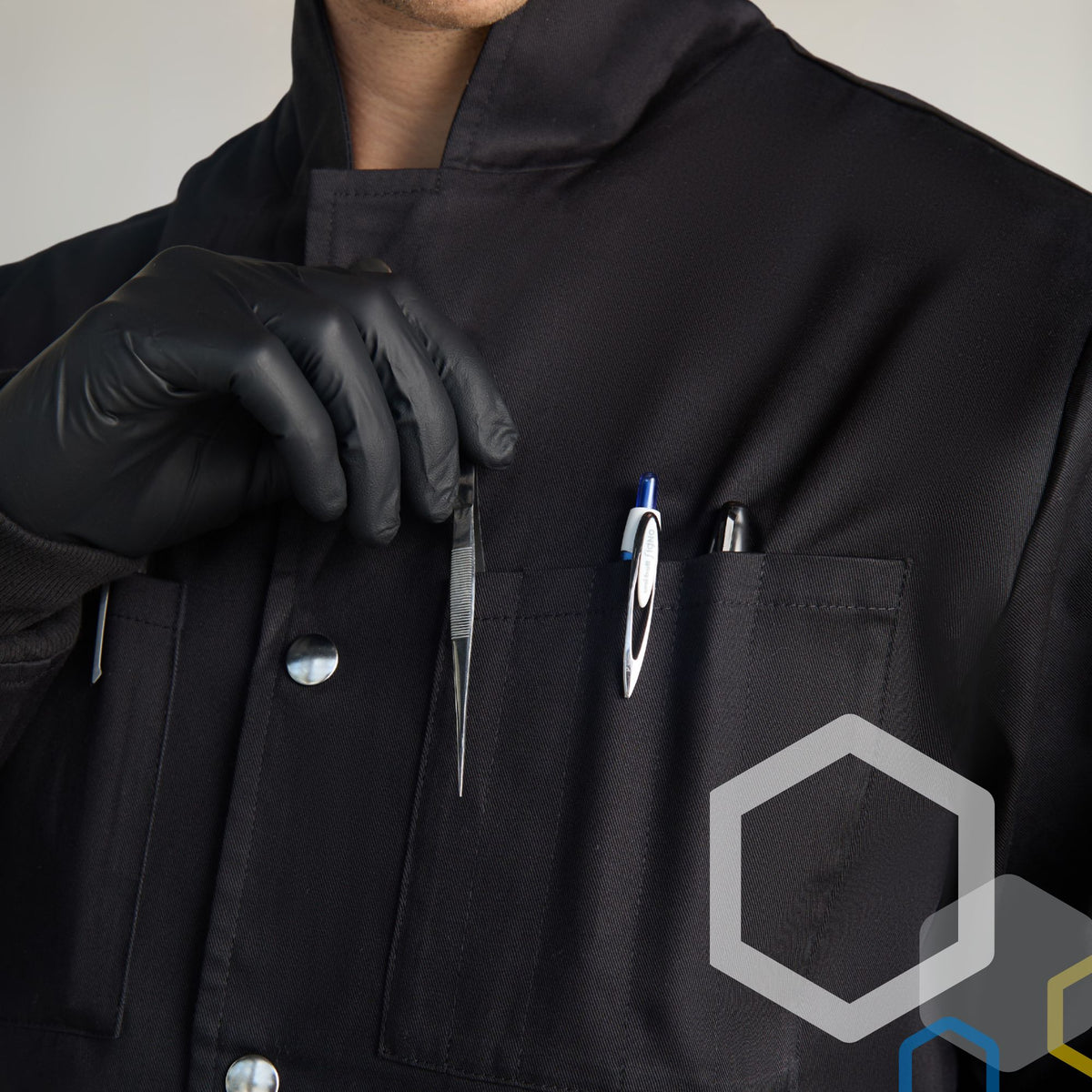 college chemistry student wearing a black 100 pct cotton lab coat and protective nitrile gloves inserting chemical lab tools in front breast pocket for storage