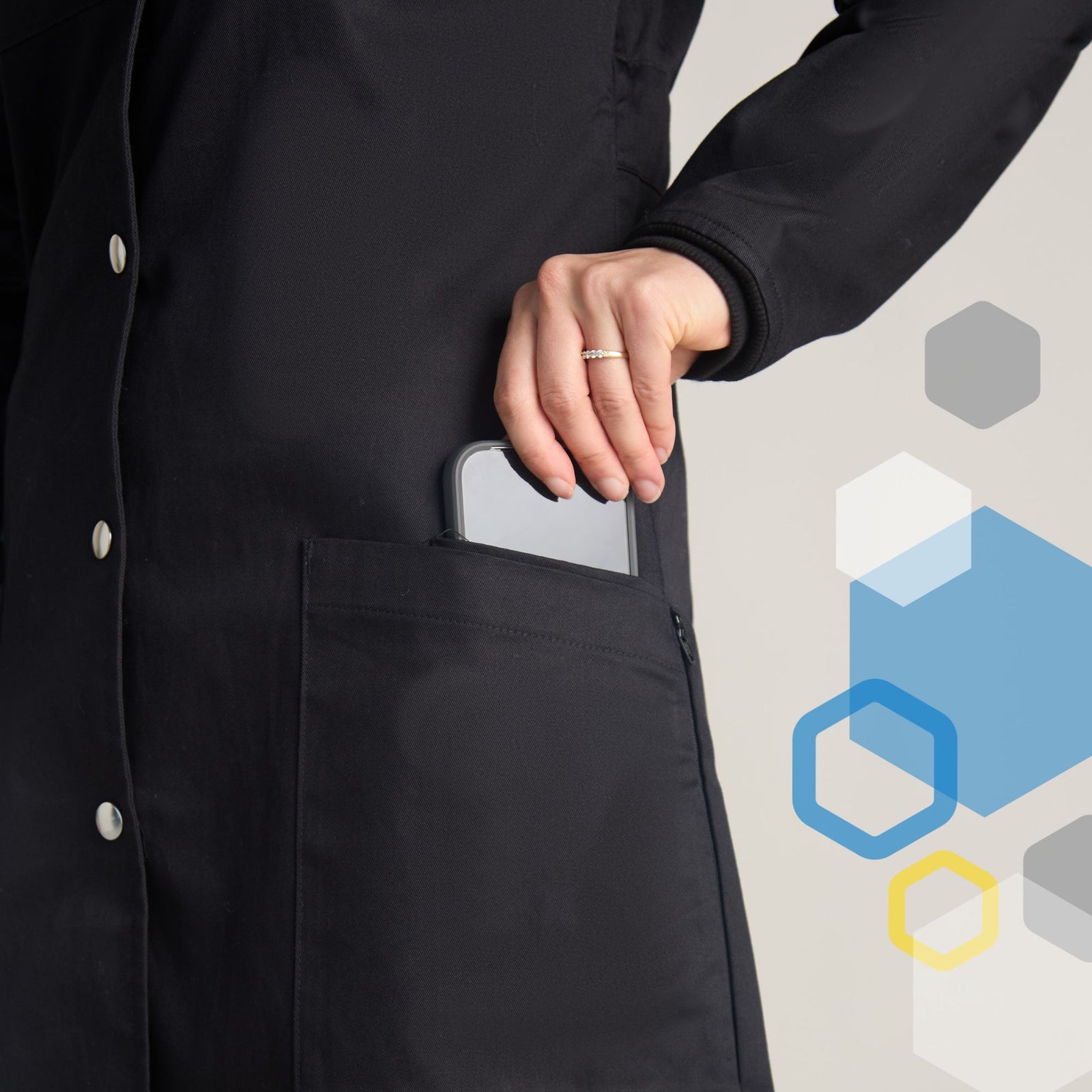 Female lab tech placing an iphone into a hidden phone pocket on lower front outside of black cotton lab coat